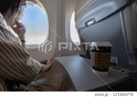 飛行機の座席のテーブルにコーヒーとスマートフォンが置かれている 飛行機の座席のテーブルにコーヒーとスマートフォンが置かれている 125868776