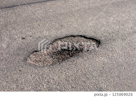 A deep pothole appears on a city street, creating possible risks for vehicles and pedestrians passing through the area A deep pothole appears on a city street, creating possible risks for vehicles and pedestrians passing through the area 125869028