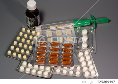 Tablets on a background with a thermometer Tablets on a background with a thermometer 125869497