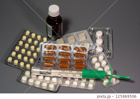 Tablets on a background with a thermometer Tablets on a background with a thermometer 125869506