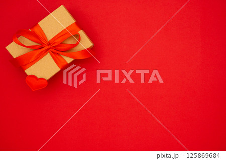 Gift box against red background. Holiday greeting card. Copy space. The concept of holidays and love Gift box against red background. Holiday greeting card. Copy space. The concept of holidays and love 125869684