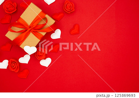 A gift in kraft box with a red bow on a red background with hearts. Valentine's day. Copy space. The concept of holidays and love 125869693
