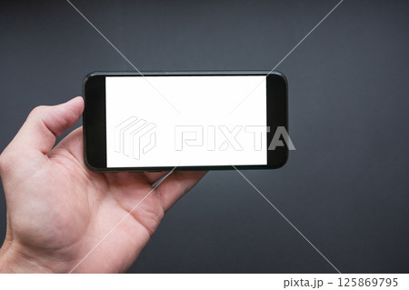 Man holding the black smartphone with blank screen. Smartphone in landscape mode 125869795