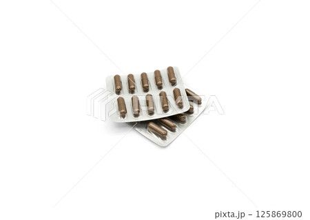Two blister packs with brown capsules isolated on a white background. Two blister packs with brown capsules isolated on a white background. 125869800