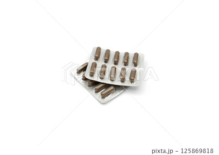 Two aluminum foil-covered blister packs with brown tablets isolated on a white background 125869818