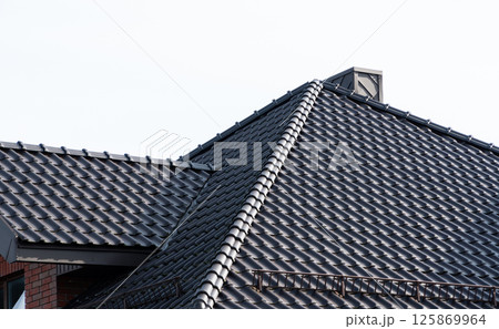 Dark brown metal roof tiles. The roof of corrugated sheet Dark brown metal roof tiles. The roof of corrugated sheet 125869964