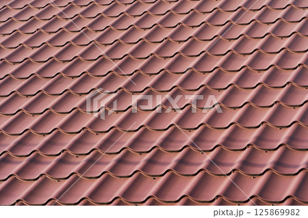 Red metal roof tiles. The texture of shingles Red metal roof tiles. The texture of shingles 125869982