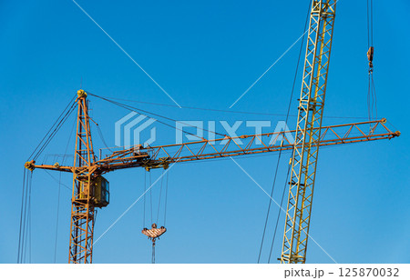 Two yellows construction cranes. Modern construction. Housing construction 125870032