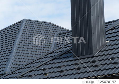 Black metal profile roof installed on a modern house. Modern types of roofing materials 125870147
