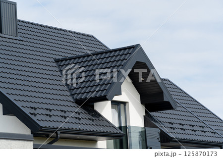The roof of a modern new house. Tiled covering of building. Modern European house The roof of a modern new house. Tiled covering of building. Modern European house 125870173