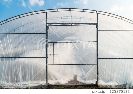 Soil greenhouse with plastic film outside view 125870182