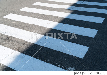 Crosswalk. New white lines of the pedestrian crossing. Application of markings on a pedestrian crossing over an asphalt road. Crosswalk. New white lines of the pedestrian crossing. Application of markings on a pedestrian crossing over an asphalt road. 125870319