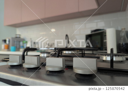 A gas stove sits centrally in a sleek kitchen with modern appliances 125870542