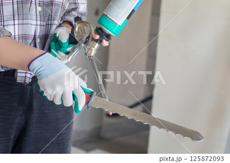 Cleaning a foam gun with a serrated knife . 125872093