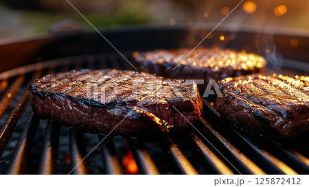 Juicy steaks sizzling on a hot grill 125872412