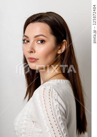 Beautiful woman in white knitted sweater posing indoors 125872484