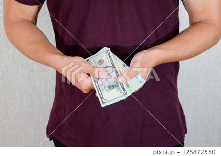 man holds a wad of dollars in his hands. US Dollars man holds a wad of dollars in his hands. US Dollars 125872580