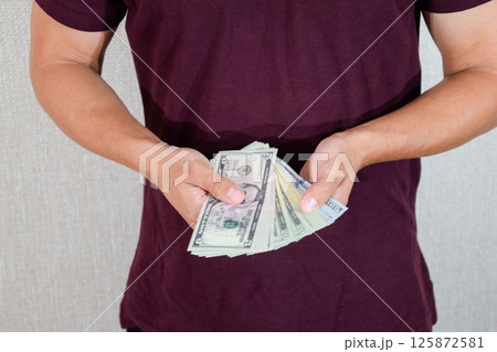 man holds a wad of dollars in his hands. US Dollars 125872581