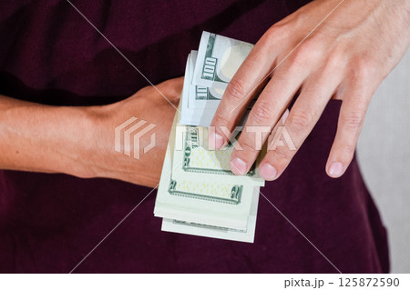 man holds a wad of dollars in his hands. US Dollars 125872590