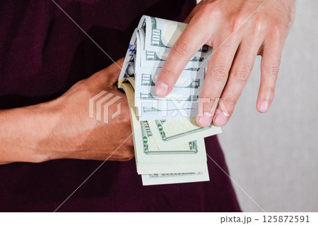 man holds a wad of dollars in his hands. US Dollars 125872591
