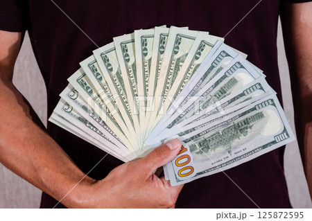 dollars are held by fan by a man in his hand. Us dollar. 125872595