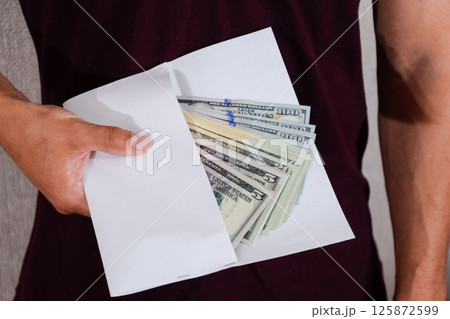 Money in white envelope in the hands of a man. Dollars, a wad of dollars. Money in white envelope in the hands of a man. Dollars, a wad of dollars. 125872599