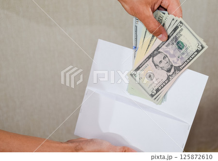 Money in white envelope in the hands of a man. Dollars, a wad of dollars. Money in white envelope in the hands of a man. Dollars, a wad of dollars. 125872610
