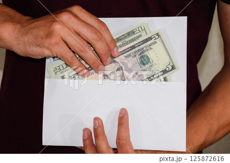 Money in white envelope in the hands of a man. Dollars, a wad of dollars. Money in white envelope in the hands of a man. Dollars, a wad of dollars. 125872616