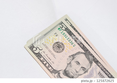 cistern of banknotes lies on a white table. Lots of dollars, a wad of dollars. 125872625