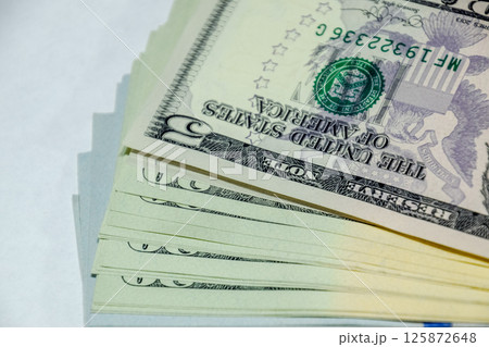 cistern of banknotes lies on a white table. Lots of dollars, a wad of dollars. 125872648