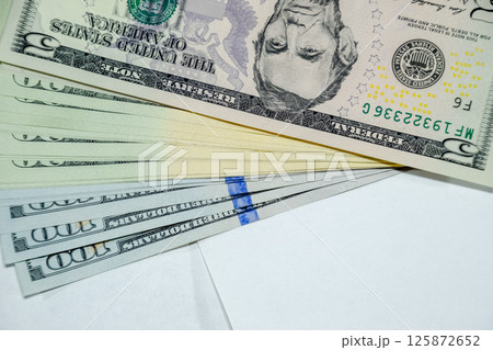 cistern of banknotes lies on a white table. Lots of dollars, a wad of dollars. 125872652