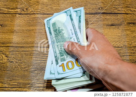 The man at table holds bills. Dollars in hand. 125872877