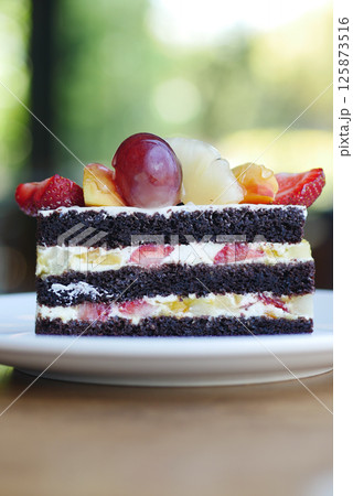 Delicious layered chocolate cake topped with fresh fruit Delicious layered chocolate cake topped with fresh fruit 125873516
