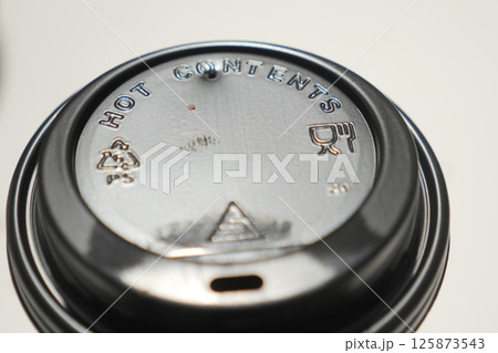 Lid of a hot beverage cup with warning symbols displayed clearly 125873543