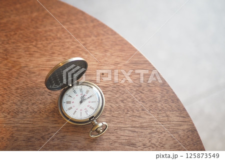 Antique pocket watch resting on a wooden table in soft lighting Antique pocket watch resting on a wooden table in soft lighting 125873549