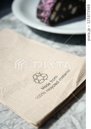 Recycled napkin placed on table near dessert in cafe setting Recycled napkin placed on table near dessert in cafe setting 125873569