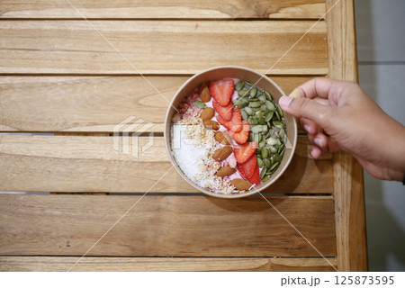 Healthy breakfast bowl with fruits and nuts on wooden table 125873595