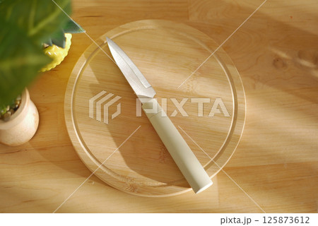 Modern kitchen knife placed on a wooden cutting board under sunlight Modern kitchen knife placed on a wooden cutting board under sunlight 125873612