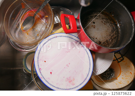 Overflowing sink full of dirty dishes after a family gathering Overflowing sink full of dirty dishes after a family gathering 125873622
