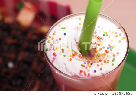 Colorful dessert drink topped with cream and sprinkles in cafe setting Colorful dessert drink topped with cream and sprinkles in cafe setting 125873659