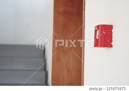 Fire alarm mounted on wall near staircase in indoor building setting 125873875