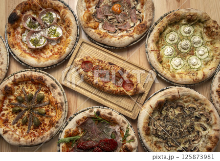 Assortment of traditional italian wood fired pizzas on table 125873981