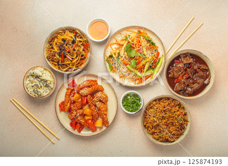 Variety of Chinese food dishes top view on table with chopsticks, light beige background, cuisine of China 125874193