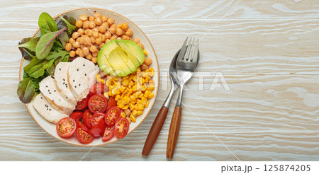 Healthy bowl with chicken breast, avocado, chickpeas, corn and tomatoes on white wooden table top view. Diet and healthy food concept 125874205