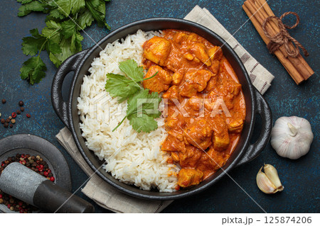 Indian dish chicken tikka masala served with rice and spices on dark blue background top view 125874206