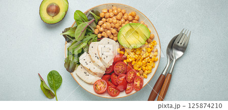 Healthy bowl with chicken breast, avocado, chickpeas, corn and tomatoes on grey background top view. Diet and healthy food concept Healthy bowl with chicken breast, avocado, chickpeas, corn and tomatoes on grey background top view. Diet and healthy food concept 125874210