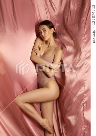 beautiful young woman on a silk background. pretty brunette girl in underwear 125874312