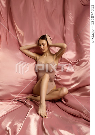 beautiful young woman on a silk background. pretty brunette model girl in underwear 125874313