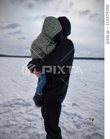Dad and child. Dad holds son tightly in his arms and covers him with his hands from the cold in winter. Dad holds his son in his arms in winter. Happy childhood of a small child. Dad and child. Dad holds son tightly in his arms and covers him with his hands from the cold in winter. Dad holds his son in his arms in winter. Happy childhood of a small child. 125874388