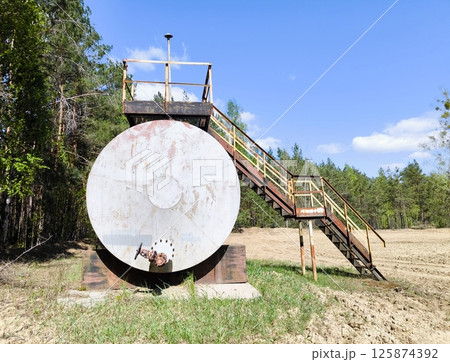 horizontal steel tank. large metal barrel with a ladder in the forest area horizontal steel tank. large metal barrel with a ladder in the forest area 125874392